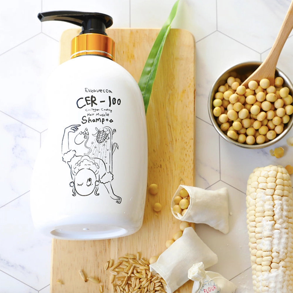 Το μπουκάλι Elizavecca CER1-100 Collagen Coating Hair Muscle Shampoo 500ml, ξαπλωμένο πάνω σε ένα ξύλινο δίσκο, δίπλα από ένα μικρό πουγκί με ρεβύθια και ένα με σιτάρι, τα οποία χύνονται και ένα ολόκληρο καλαμπόκι με ένα μεταλλικό μπολάκι γεμάτο με ρεβύθια και ένα ξύλινο κουτάλι.