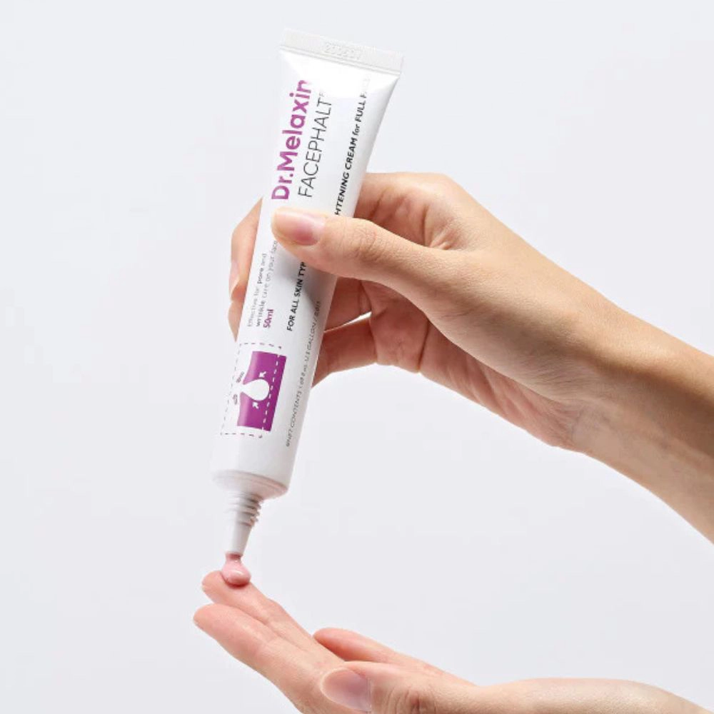Ένα χέρι κρατάει το σωληνάριο Dr. Melaxin Facephalt Tightening Cream και βάζει κρέμα στο άλλο χέρι.