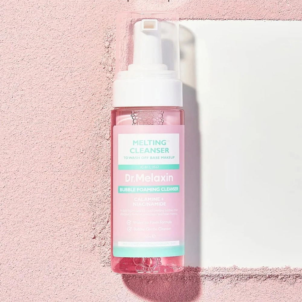 Το μπουκάλι Dr. Melaxin Melting Cleanser, "καθαρίζει" μία ροζ άμμο.