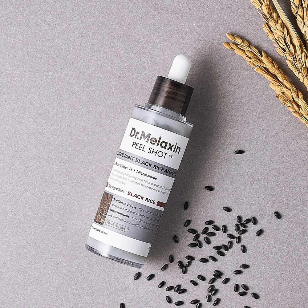 Το μπουκάλι Dr. Melaxin Peel Shot Exfoliant Black Rice Ampoule πάνω σε λίγο μαύρο ρύζι και μερικά στάχια.