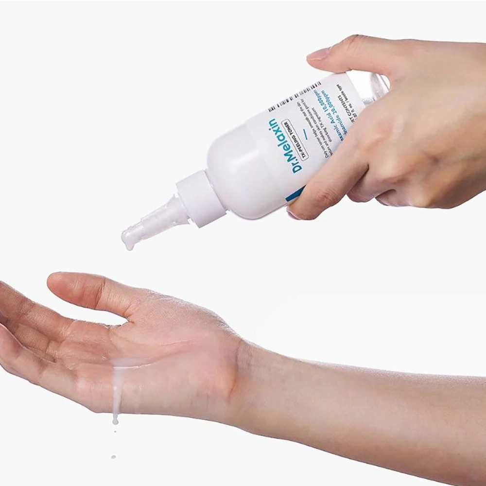 Ένα χέρι κρατάει το μπουκάλι Dr. Melaxin TX Peeling Toner και στάζει προϊόν στο άλλο χέρι.